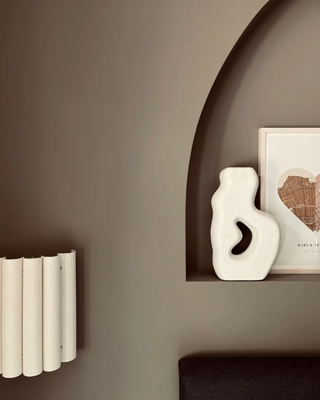 Ronde wandnis met witte sculptuurvaas, print en een geribbelde wandlamp