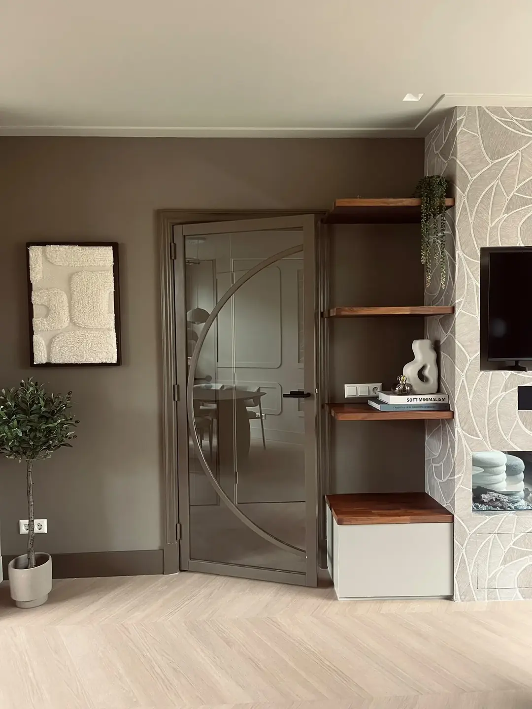 Boogvormige glazen deur met wandplanken, olijfboom en behang met bladmotief