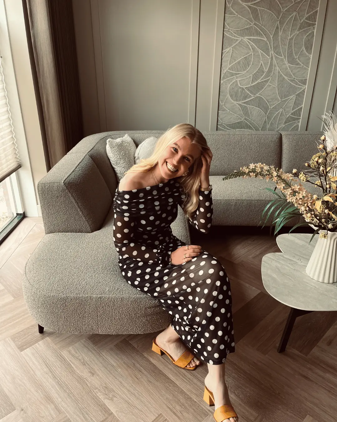 Trijntje Laan lacht, zittend op een bouclé bank in een lichte woonkamer