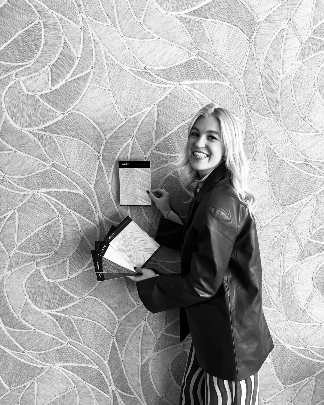 Zwart-witportret van Trijntje Laan met stalenboeken voor een behangwand